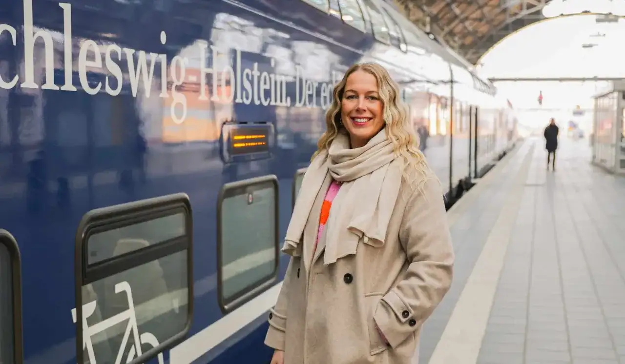Frau am Bahnsteig in Schleswig-Holstein, bereit für neue Abenteuer. Hier sind einige Flensburg Tipps für deine Reise!