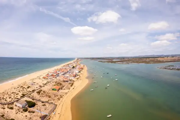 Faro: Was tun? Eine Küstenstadt mit Sandstrand, Häusern und vielen Booten im Wasser. Perfekt für einen entspannten Urlaub.