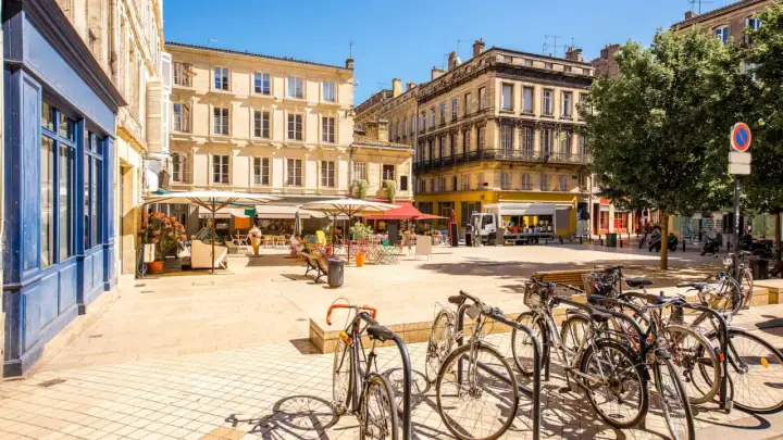 Sonniger Platz in Bordeaux mit Cafés, Fahrrädern und charmanten Gebäuden – ein echter bordeaux geheimtipp.
